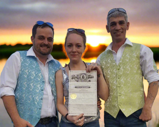 Three people standing outdoors with a woman holding a certificate.